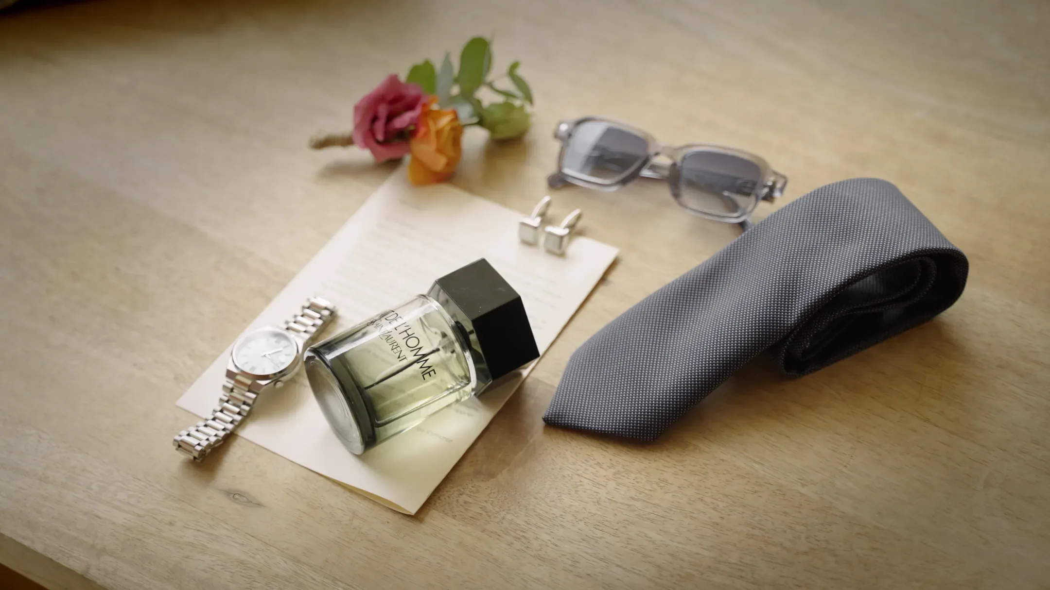 Montre, parfum, cravate et boutonnière du marié posés sur une table