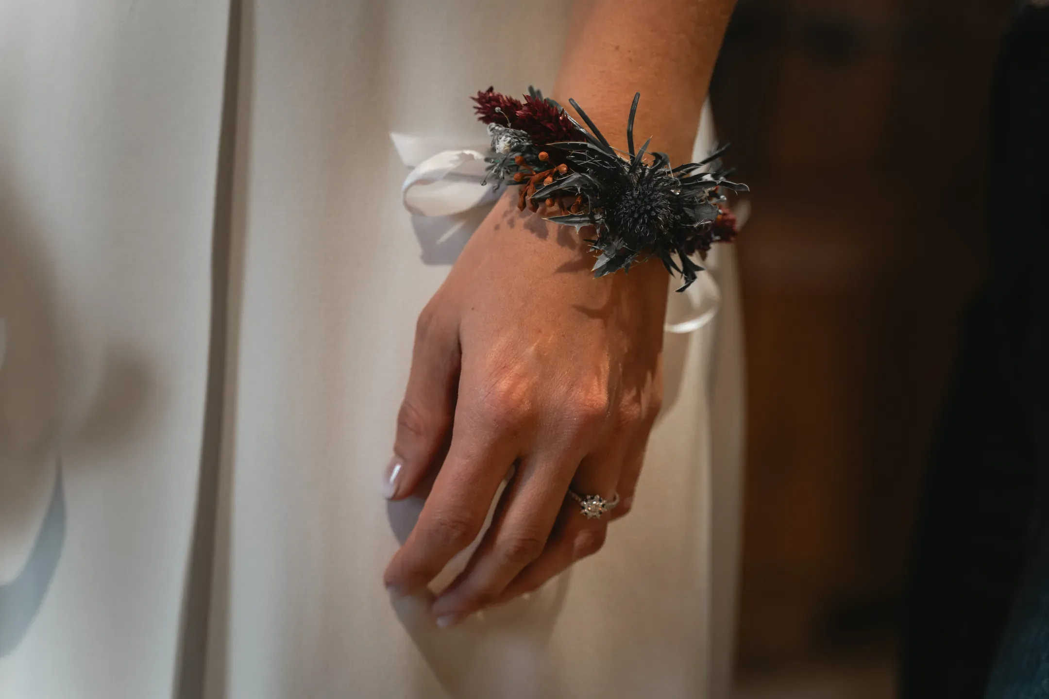 Main de la mariée portant une bague et un bracelet de fleurs séchées