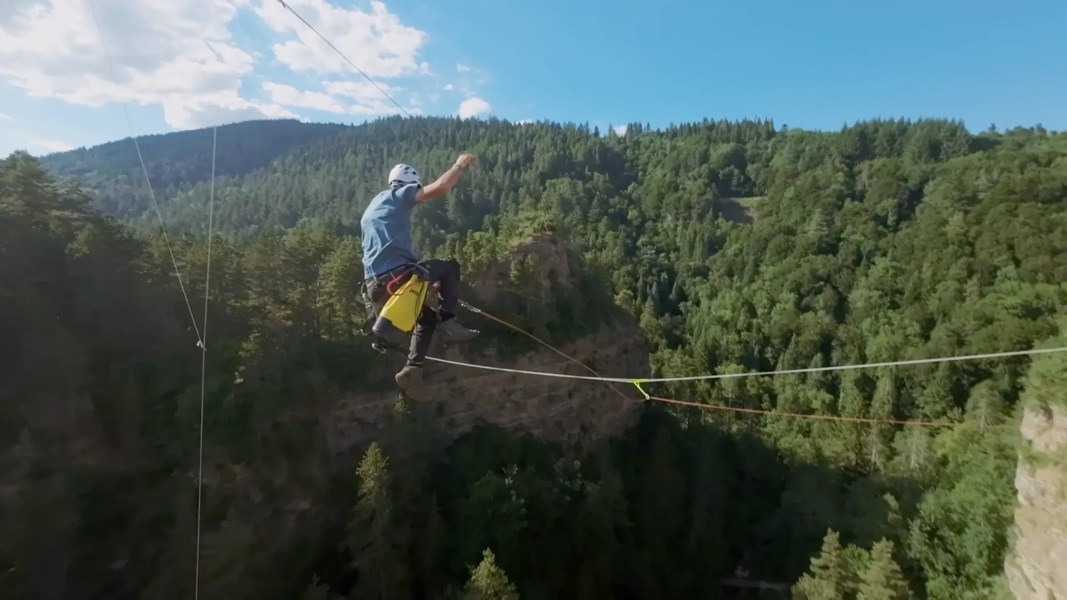 Saut pendulaire au-dessus d'une gorge boisée, vu de loin