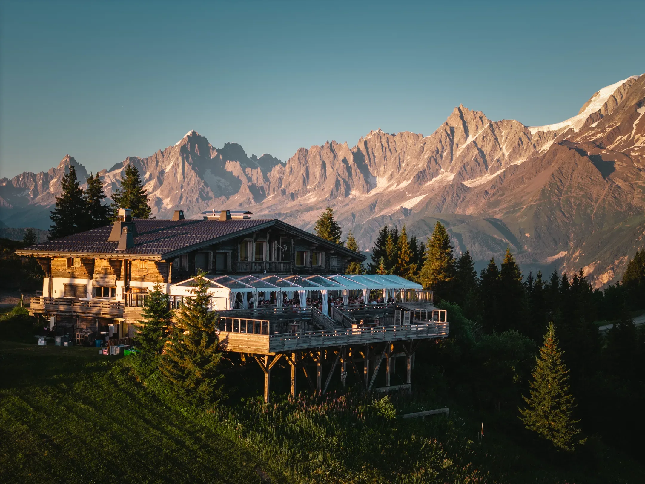 Chalet d'altitude dans la lumière dorée du soir, sommets en arrière-plan