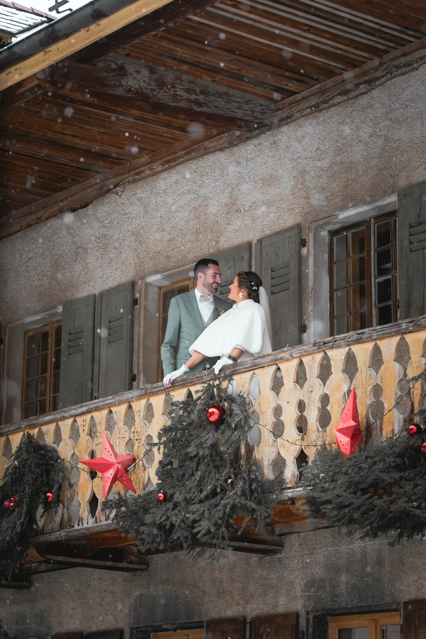 Les mariés au balcon d'un chalet décoré pour l'hiver