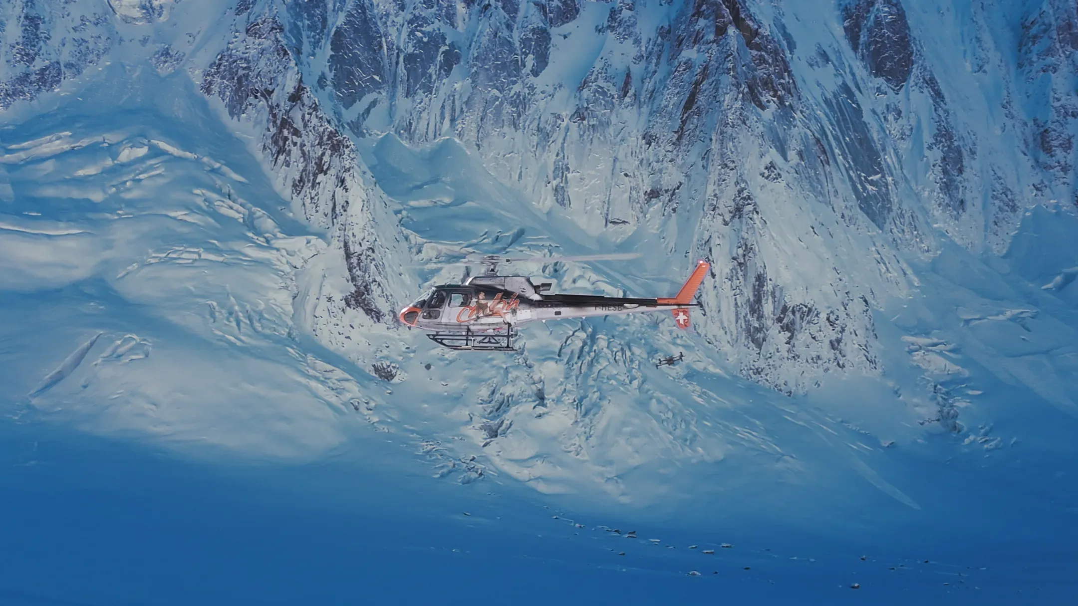 Hélicoptère en vol au-dessus de montagnes enneigées, vu du dessus