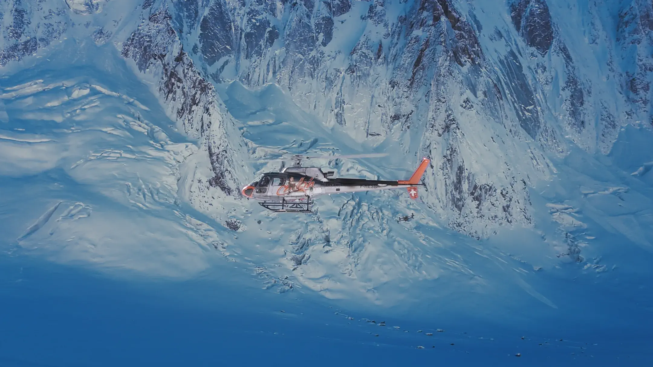 Hélicoptère en vol au-dessus de montagnes enneigées, vu du dessus