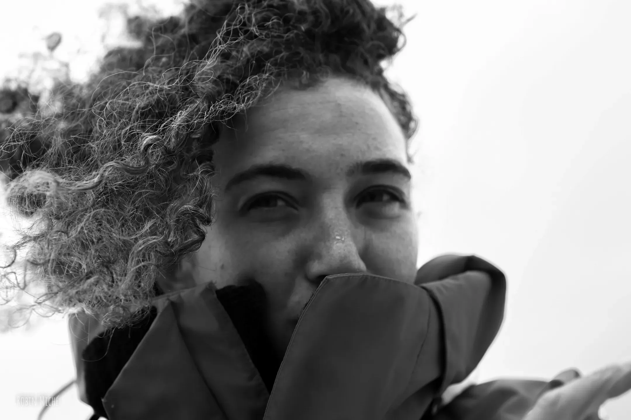 Portrait en noir et blanc d'une navigatrice souriante, le col de sa veste relevé