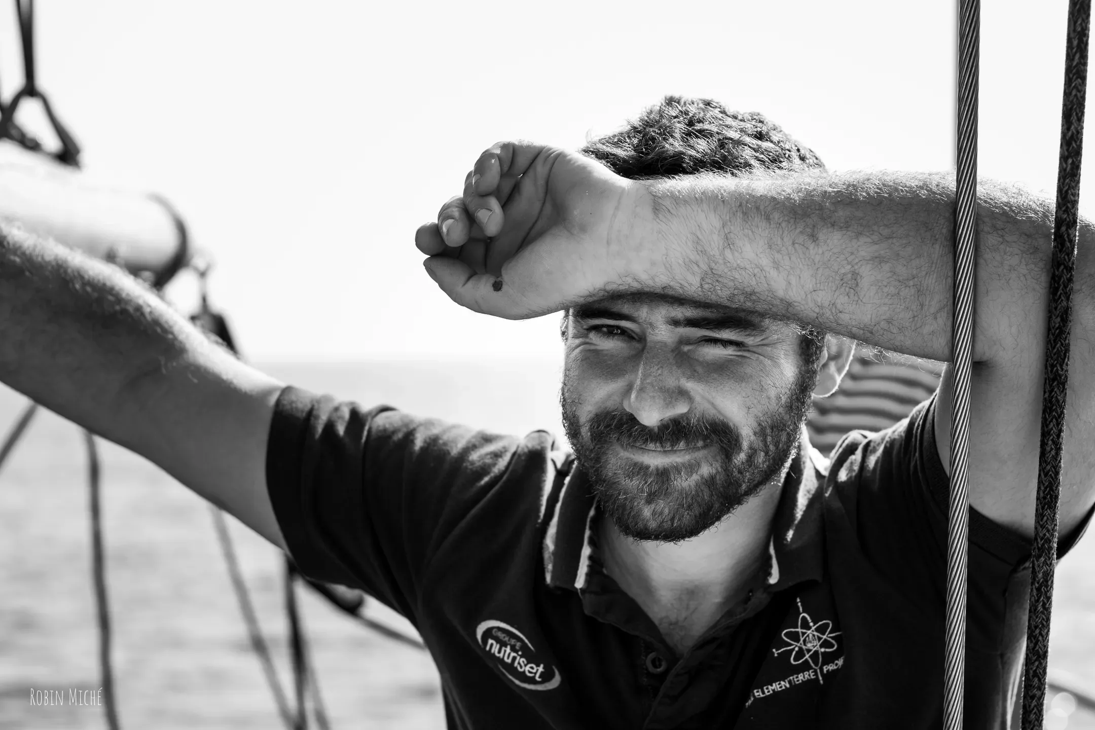 Portrait en noir et blanc d'un marin souriant, le bras appuyé sur le front