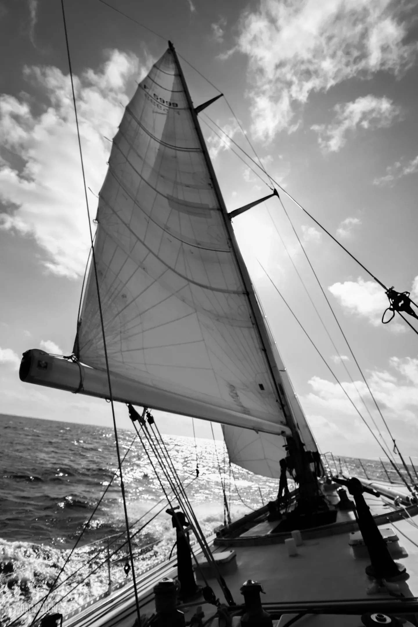 Voilier sous voiles en pleine mer, photographié en noir et blanc depuis le pont