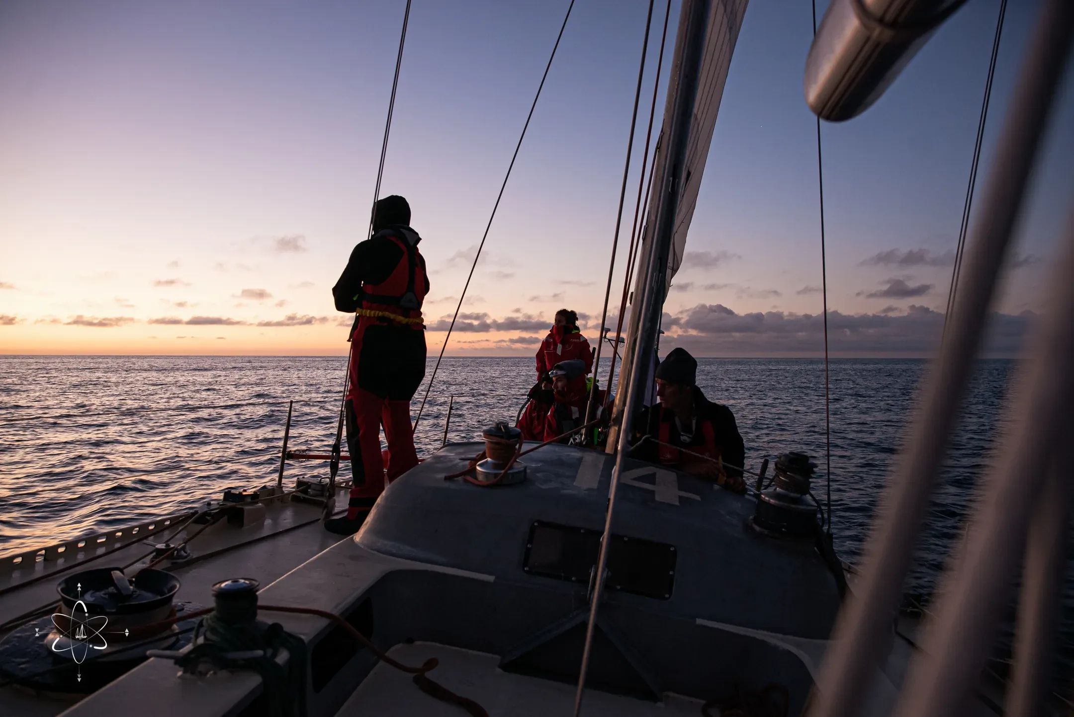 Équipiers sur le pont du voilier face au coucher du soleil sur la mer