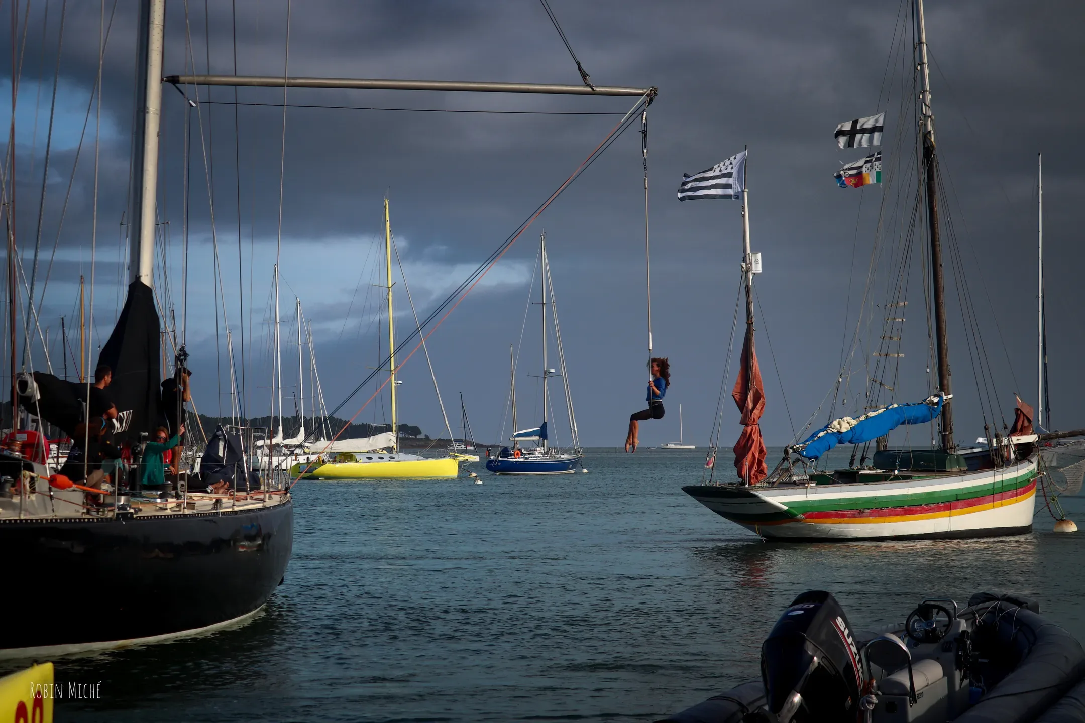 Voiliers au mouillage, pavillons hissés, sous un ciel d'orage