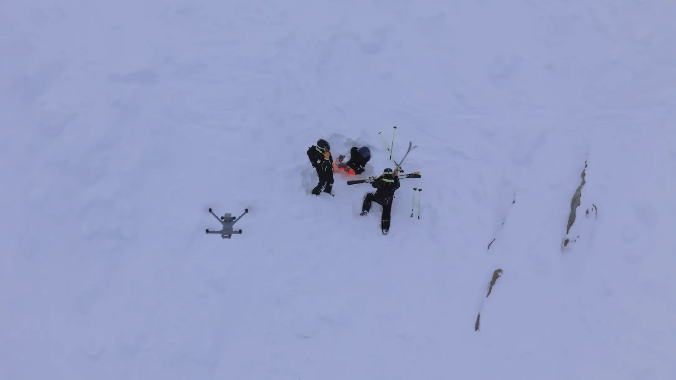 Vue plongeante d'un groupe en exercice dans la neige, un drone posé à côté