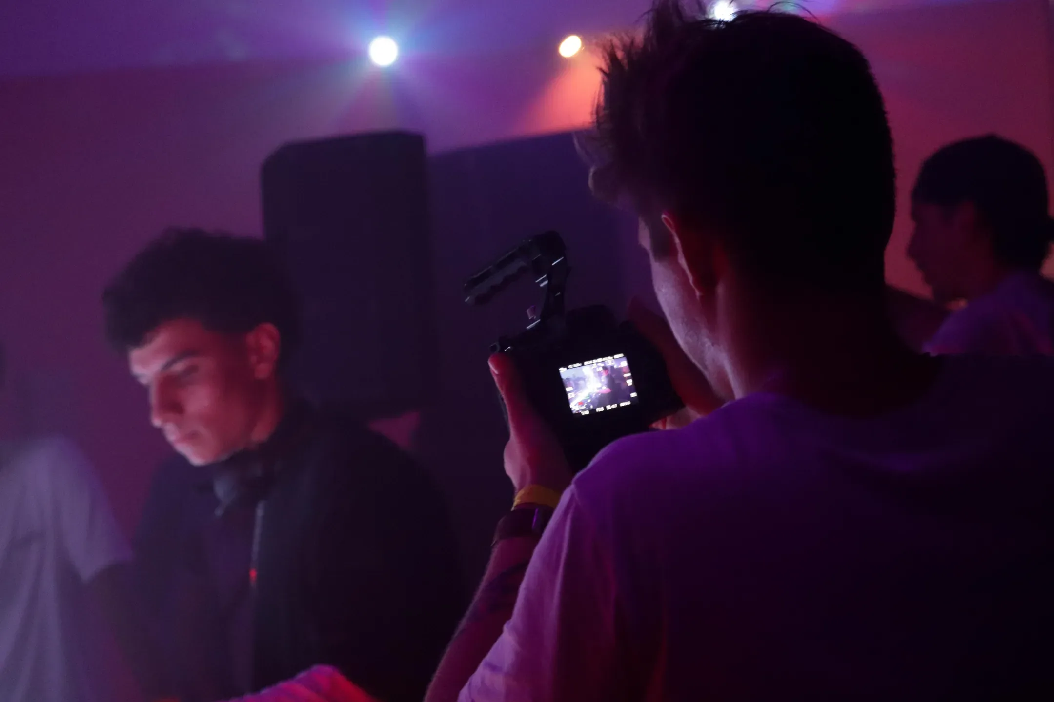 Vidéaste filmant le DJ, l'écran de la caméra en premier plan