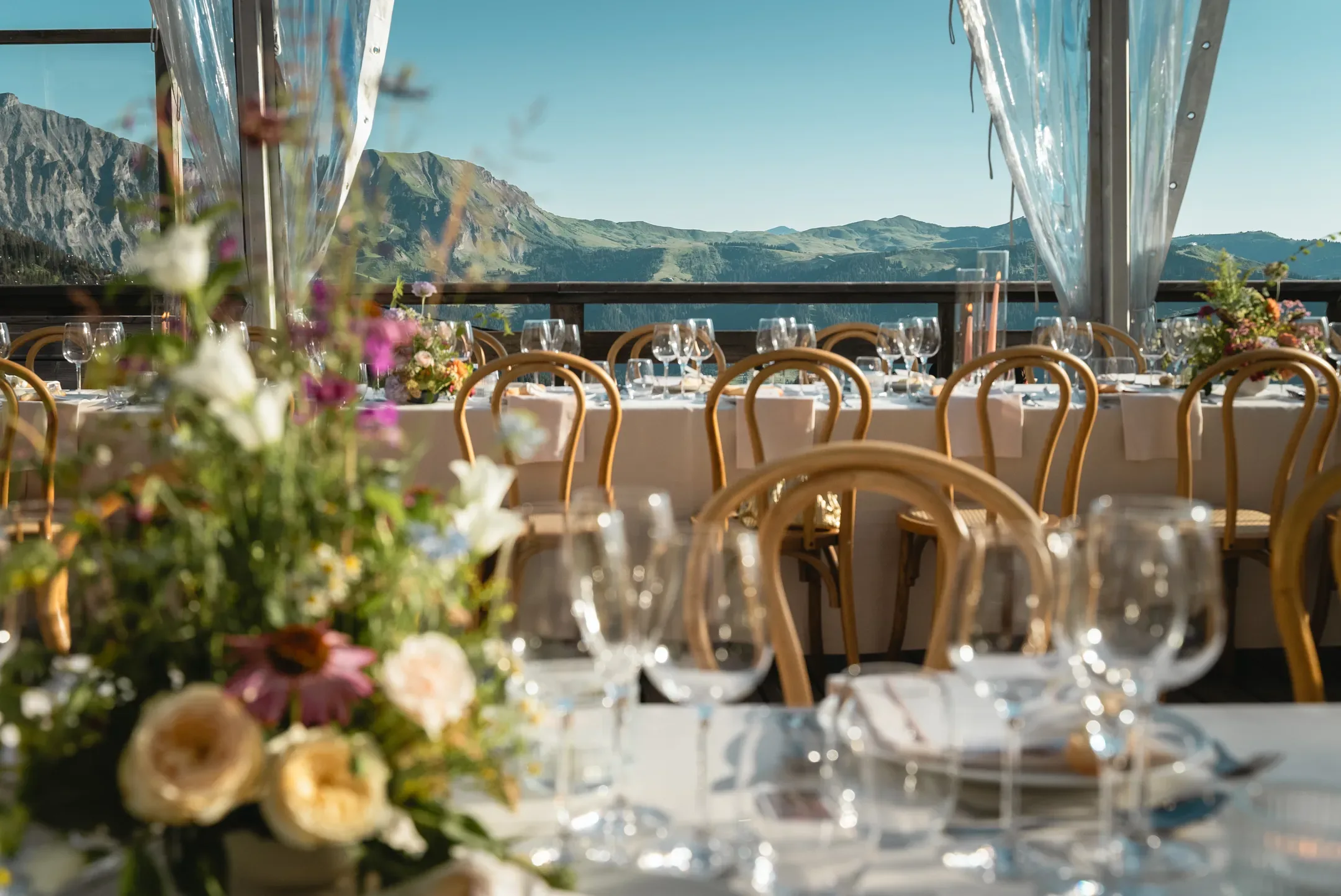 Tables dressées avec des bouquets sous une tente transparente, vue sur les montagnes